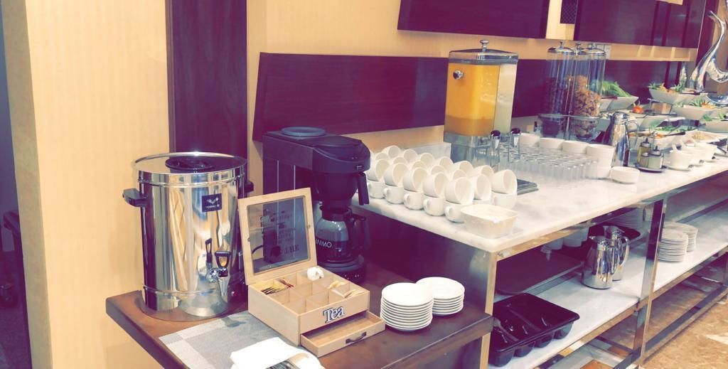 Un buffet proposant des machines à café, des distributeurs de thé et une variété de plats et de boissons.