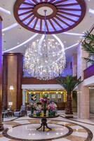 A lobby with a grand chandelier, a reception desk, and a seating area.