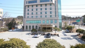 A multi-story hotel with a modern facade, a covered entrance, and a parking lot with several cars. - Uljin Grand Hotel (Uljin)