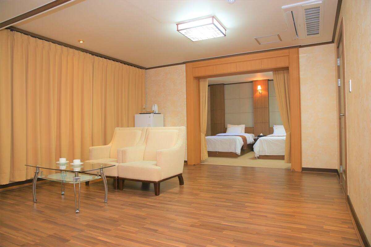 A hotel room with a glass table, a sofa, and a bed.