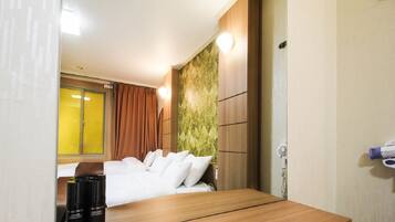 Habitación de hotel con una cama, una mesa de madera, un espejo y una pared con un diseño texturizado.