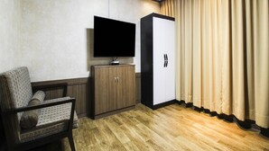 A room with a wooden floor, a sofa, a TV on a stand, a wardrobe, and curtains. - Uljin Grand Hotel (Uljin)