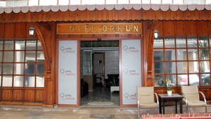 Exterior de un hotel llamado "OTEL ORKUN", con fachada de madera tradicional, ventanas amplias y un cartel sobre la entrada.