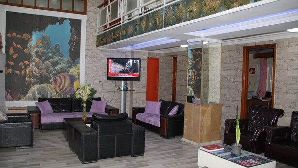 Un vestíbulo amplio con un gran mural de acuario, asientos cómodos y un televisor sobre un soporte.