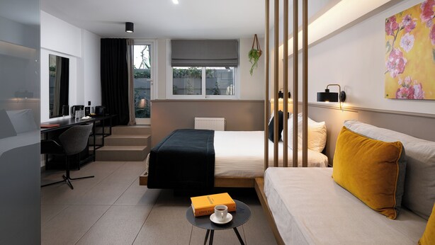 Una habitación de hotel moderna con cama, sofá, escritorio y zona de comedor.