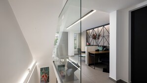 Un interior moderno con un separador de vidrio, un escritorio con computadora y un elemento decorativo en la pared.