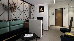 Una moderna zona de recepción con un sofá verde, un expositor de mármol blanco y un logotipo enmarcado en la pared.