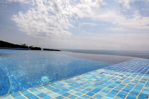 A clear blue infinity pool with a tiled edge, overlooking a beach and ocean. - Lighthouse Luxe Estate Apart & Villas (Balchik)