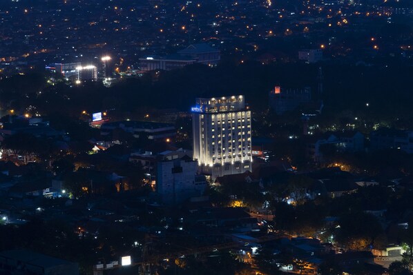 Un hotel moderno de gran altura con ventanas iluminadas, rodeado por un paisaje urbano nocturno.