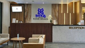A hotel reception area with a reception desk, a television, and seating.