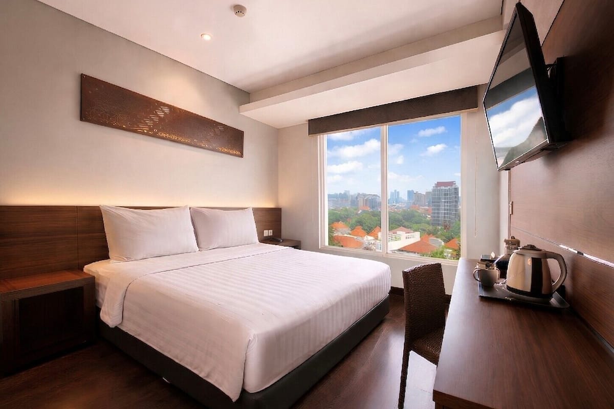 Une chambre d’hôtel avec un grand lit, une télévision, une machine à café et une vue sur le paysage urbain.