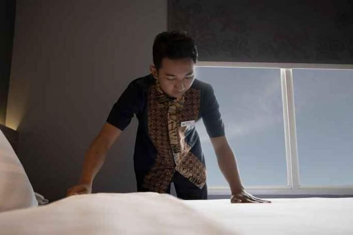 Une personne est en train de régler un lit dans une pièce dotée d’une grande fenêtre.