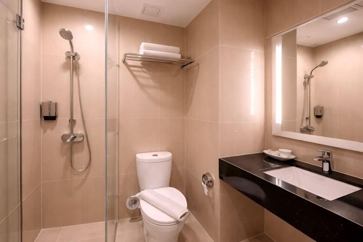 Une salle de bain moderne avec une douche à parois de verre, des toilettes, un lavabo avec un miroir et un porte-serviettes.
