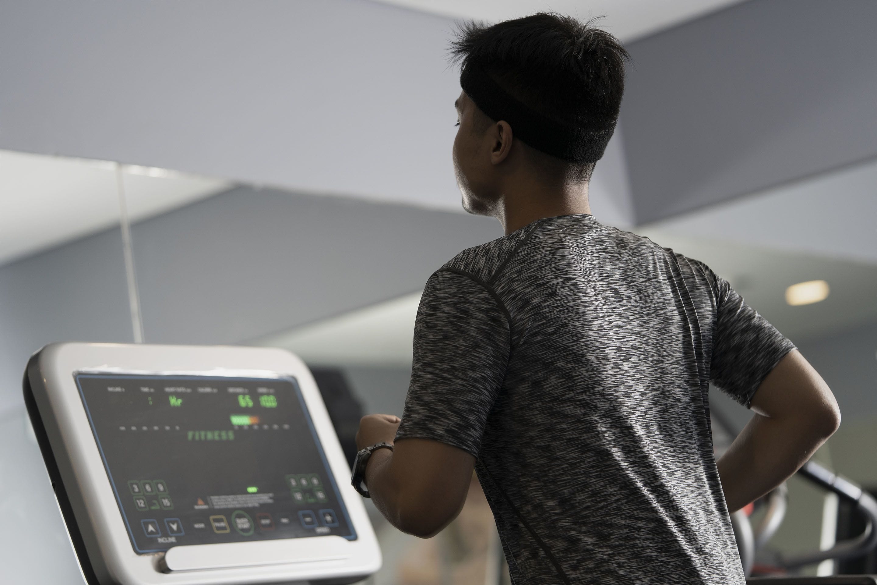 A person using a stationary bike in a gym with a digital display.
