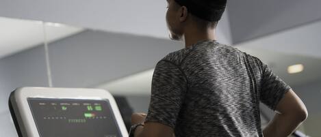 A person using a stationary bike in a gym with a digital display.
