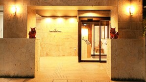 The entrance to Smart Condo Tomari with a stone facade, two red lion statues, and a sign above the door.