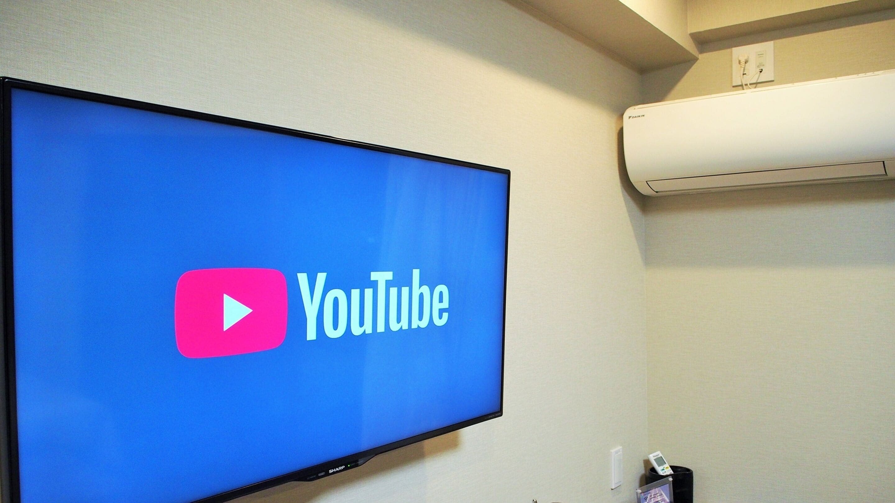 Televisão de tela plana fixada na parede exibindo o logotipo do YouTube.