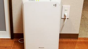 A white Daikin air conditioner unit with a power cord plugged into a wall socket.
