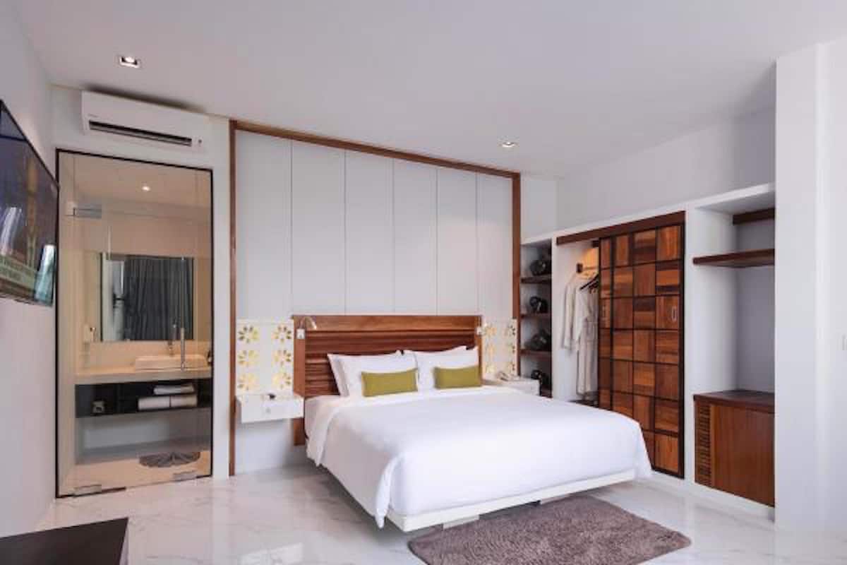 A modern bedroom with a large bed, a walk-in closet, and a bathroom with a glass shower enclosure.