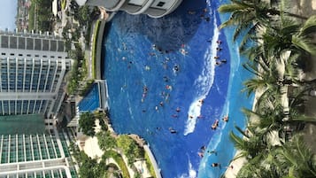 A large indoor swimming pool with multiple lanes, surrounded by palm trees and modern buildings.