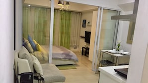 A modern apartment with a bed, a sofa, a desk, and a TV. - Family Condo by IA at Azure Urban Resort Residences (Parañaque)
