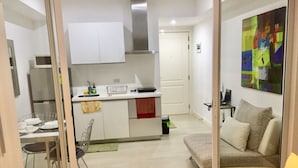 A compact living space with a kitchenette, a dining area, and a sofa. - Family Condo by IA at Azure Urban Resort Residences (Parañaque)