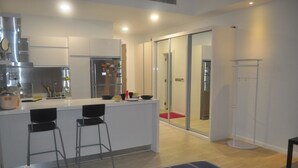 A modern kitchen with a central island, two bar stools, and a refrigerator with magnets. - Studio M City Jalan Ampang by Fervent (Kuala Lumpur)