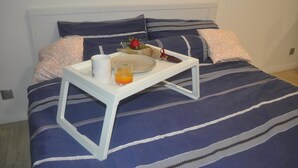 A bed with a tray table holding a plate, a glass of orange juice, and a small decorative item. - Studio M City Jalan Ampang by Fervent (Kuala Lumpur)