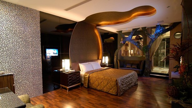 A modern hotel room with a large bed, a desk, a TV, and a unique ceiling sculpture. - Romantic Code Motel (Tainan)