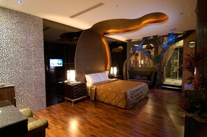 Een moderne hotelkamer met een groot bed, een bureau, een televisie en een unieke sculptuur aan het plafond.
