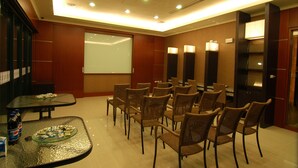 A conference room with a glass table, wicker chairs, a projector screen, and a buffet table with food. - Romantic Code Motel (Tainan)