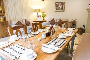 Un comedor con una larga mesa de madera dispuesta para una comida, rodeado de sillas.