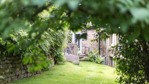 Un bâtiment en pierre doté d’une terrasse en bois et d’un escalier menant à une porte.