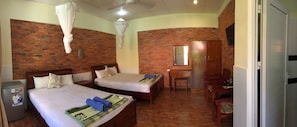 A hotel room with two beds, a desk, a chair, a mirror, and a refrigerator. - Nhat Quang Family Beach (Mui Ne)