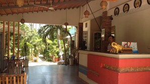 Zona de recepción con mostrador de madera, una recepcionista y un cartel de recepción.