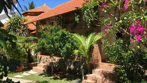 Un patio con techo de tejas, plantas en macetas y una escalera que lleva a un edificio.