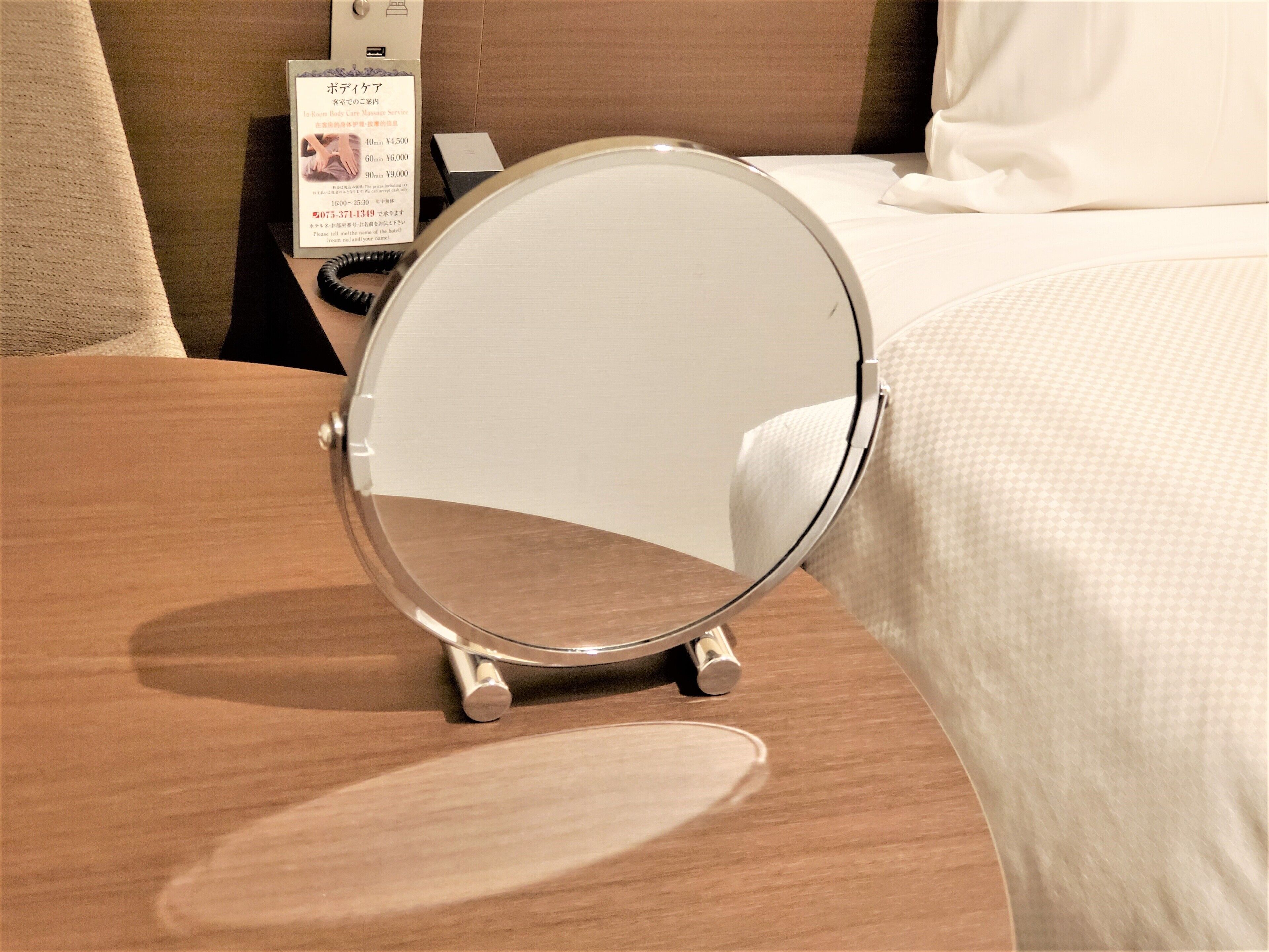Een ronde spiegel op een houten tafel in een hotelkamer.