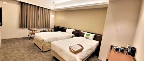 Una habitación de hotel con dos camas, un escritorio pequeño, una silla y una ventana con cortinas.