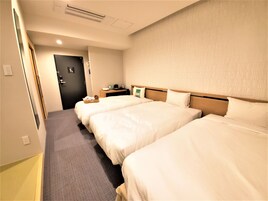 Una habitación de hotel con dos camas, una mesita de noche y una puerta.