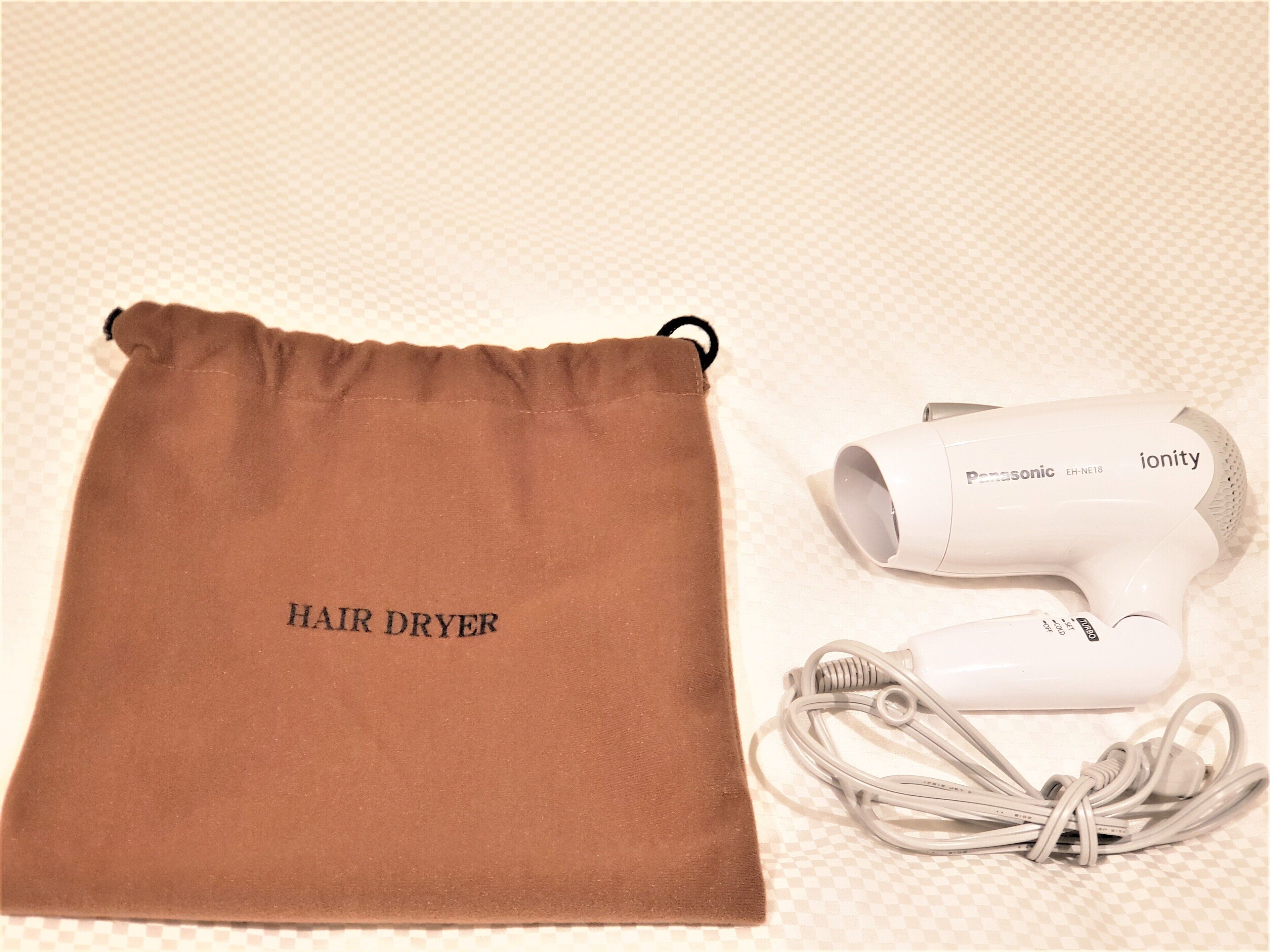 A hair dryer and its accessories on a checkered surface.