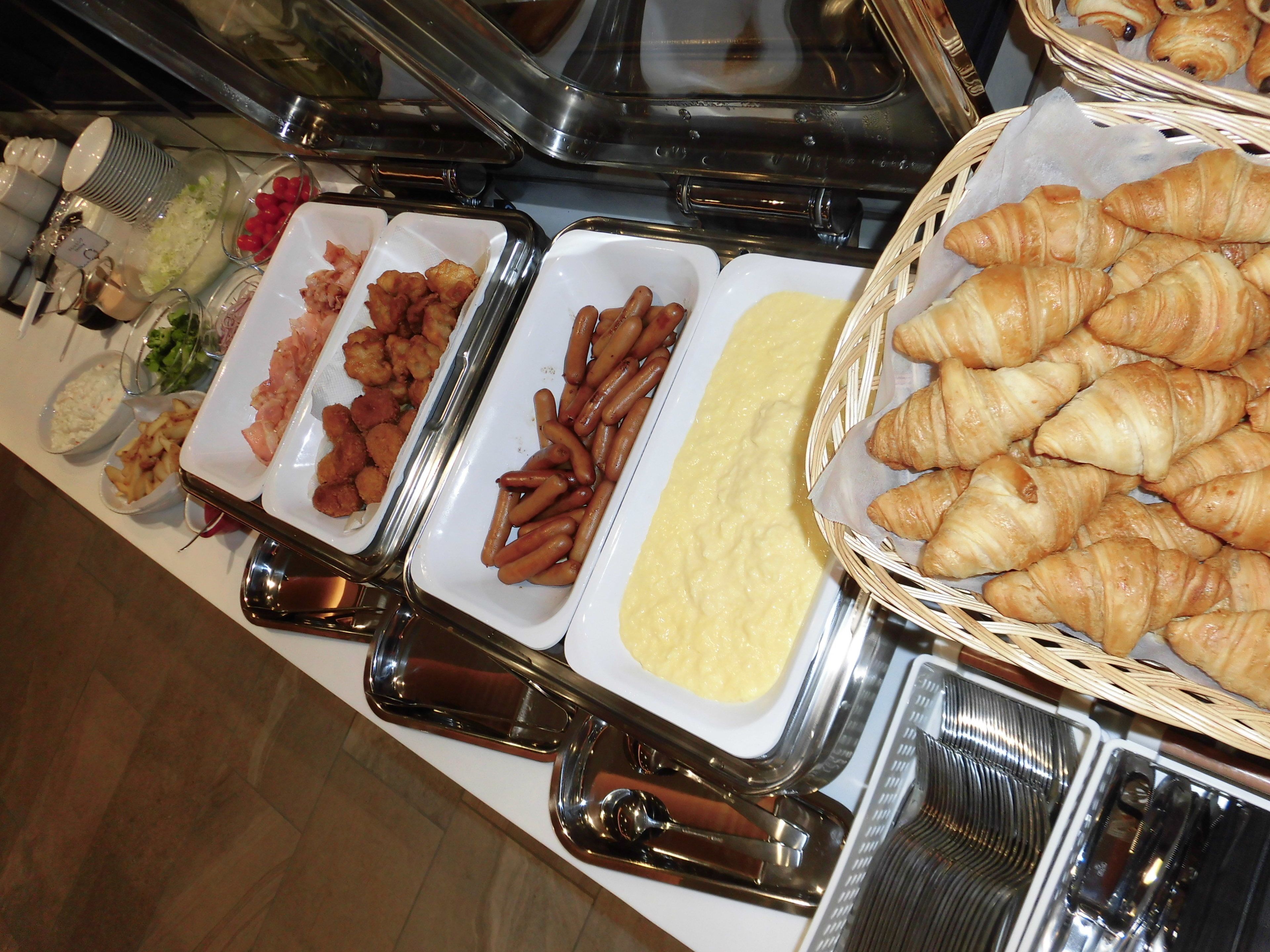 Ein Buffet mit verschiedenen Speisen, darunter Fleisch, Kartoffeln und Gebäck.