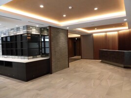A modern reception area with a reception desk, a glass partition, and a wooden panel wall.