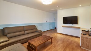 A living room with a brown leather sofa, a wooden coffee table, and a flat-screen TV mounted on the wall. - Pyeongchang Hotel The Maru (Pyeongchang)
