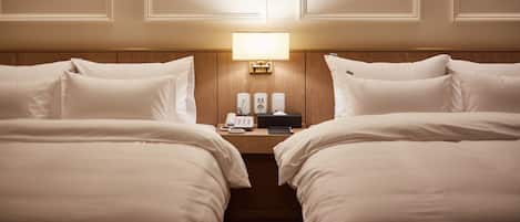 Una habitació d'hotel amb dos llits, una taula de nit amb una làmpada, un telèfon i un altaveu.