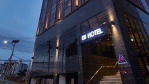 A modern hotel building with a prominent sign, a staircase leading to the entrance, and a clear sky in the background. - Pyeongchang Hotel The Maru (Pyeongchang)