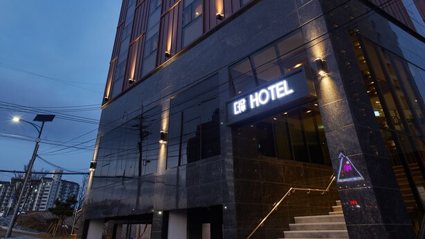 A modern hotel building with a prominent sign, a staircase leading to the entrance, and a clear sky in the background. - Pyeongchang Hotel The Maru (Pyeongchang)