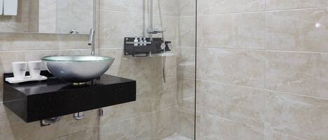 A modern bathroom with a glass-enclosed shower, a large mirror, and a sink with a vessel basin.