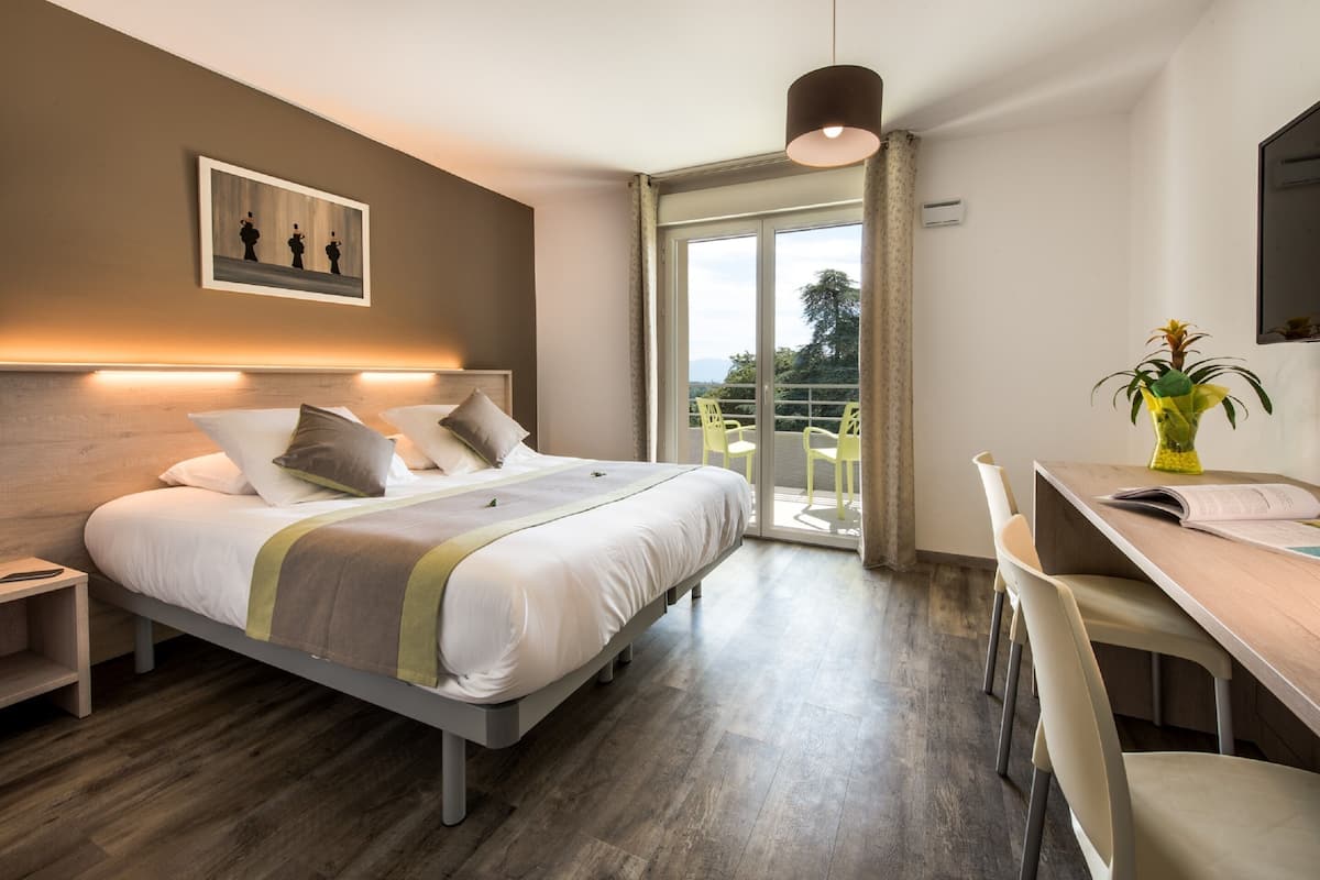A modern bedroom with a bed, bedside table, and a desk with chairs.