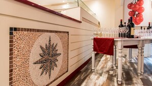 Ein Empfangsbereich mit einer Mosaikwand, einer Treppe und einem Tisch mit Weinflaschen und Gläsern.
