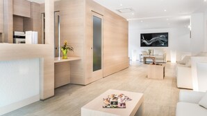 Eine moderne Hotelhalle mit Rezeption, Sitzgelegenheiten und einem großen Flachbildfernseher an der Wand.